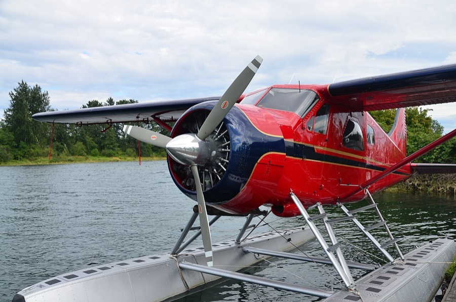 Red de Havilland Beaver floatplane tied up at a dock on calm water
